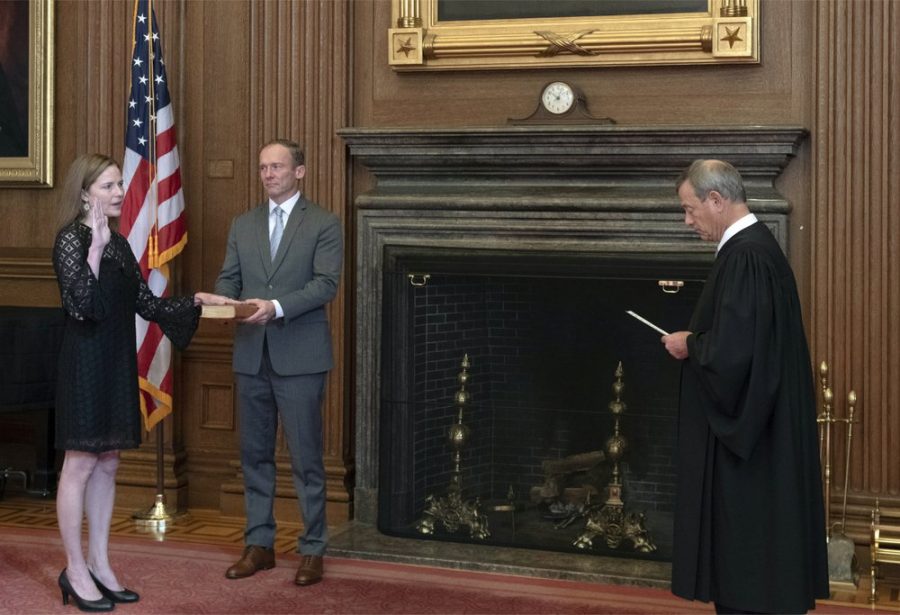 In this image provided by the Collection of the Supreme Court of the United States, Chief Justice John G. Roberts, Jr., right, administers the Judicial Oath to Judge Amy Coney Barrett in the East Conference Room of the Supreme Court Building, Tuesday, Oct. 27, 2020, in Washington as Judge Barretts husband, Jesse M. Barrett, holds the Bible. (Fred Schilling/Collection of the Supreme Court of the United States via AP)