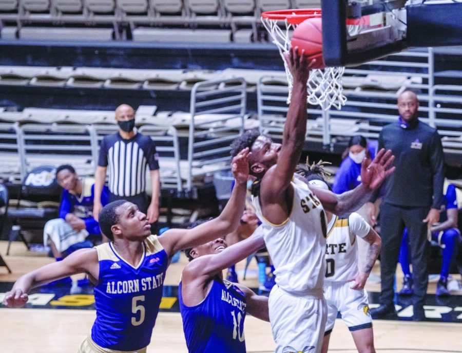 Alabama State University Hornet Brandon Battle competing on the boards against two Alcorn State University Brave defenders.