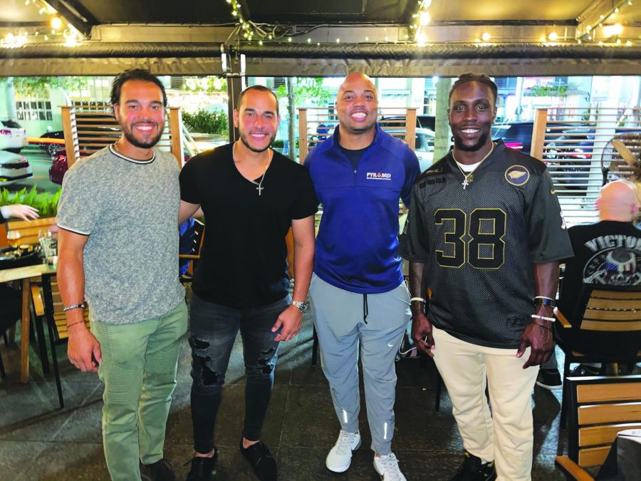 Before sitting down to enjoy lunch, alumnus Orlando Arnold (third from left) takes a moment to pose with the professional athletes that he represents.  Those athletes are Anthony Gomez who is a member of the Washington Nationals Organization, Rusber Estrada, a member of the Atlanta Braves Organization, and (far right) Jonathan Ward, a running back for the Arizona Cardinals. 