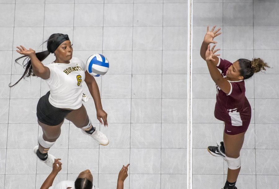 Junior middle blocker, Mahogany Vinson spikes the ball past a Bulldogs player, en-route to a sweep in their home opener.