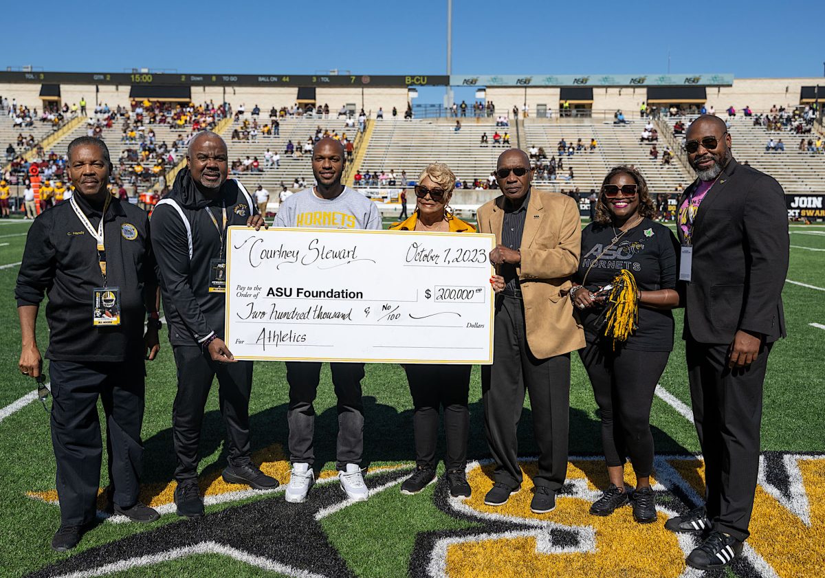 During the Homecoming football game, Courtney Stewart presents a check to President Quinton T. Ross Jr., Ed.D.  He is joined by Stewart’s mother, father and sister along with Athletic Director Jason Cable and Alumini Affairs Director Cromwell Hand

Photo by David Campbell/Alabama State University