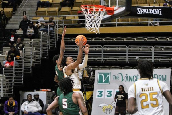 Mississippi Valley State University Delta Devil defender attempts to block the shot of Alabama State University Hornet guard T.J.Madlock as he powers through the contact and goes up for a layup during the contest.